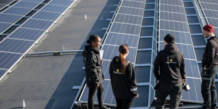 Fyra personer framför solcellsanläggning